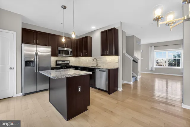 a kitchen with a refrigerator a sink dishwasher a dining table and chairs with wooden floor