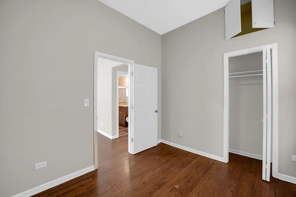 a view of an empty room with wooden floor and closet