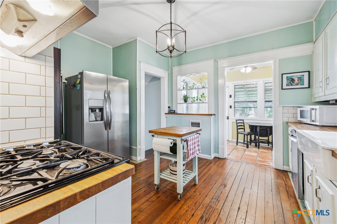 1004 Mitchell Street Gonzales, TX 78629 - Photo 13 of 46 a kitchen with stainless steel appliances granite countertop a stove refrigerator and a dining table with wooden floor