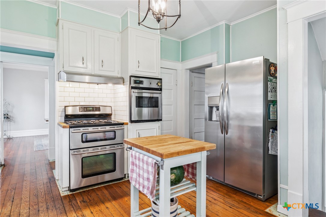 1004 Mitchell Street Gonzales, TX 78629 - Photo 15 of 46 a kitchen with stainless steel appliances kitchen island granite countertop a refrigerator a stove and a sink