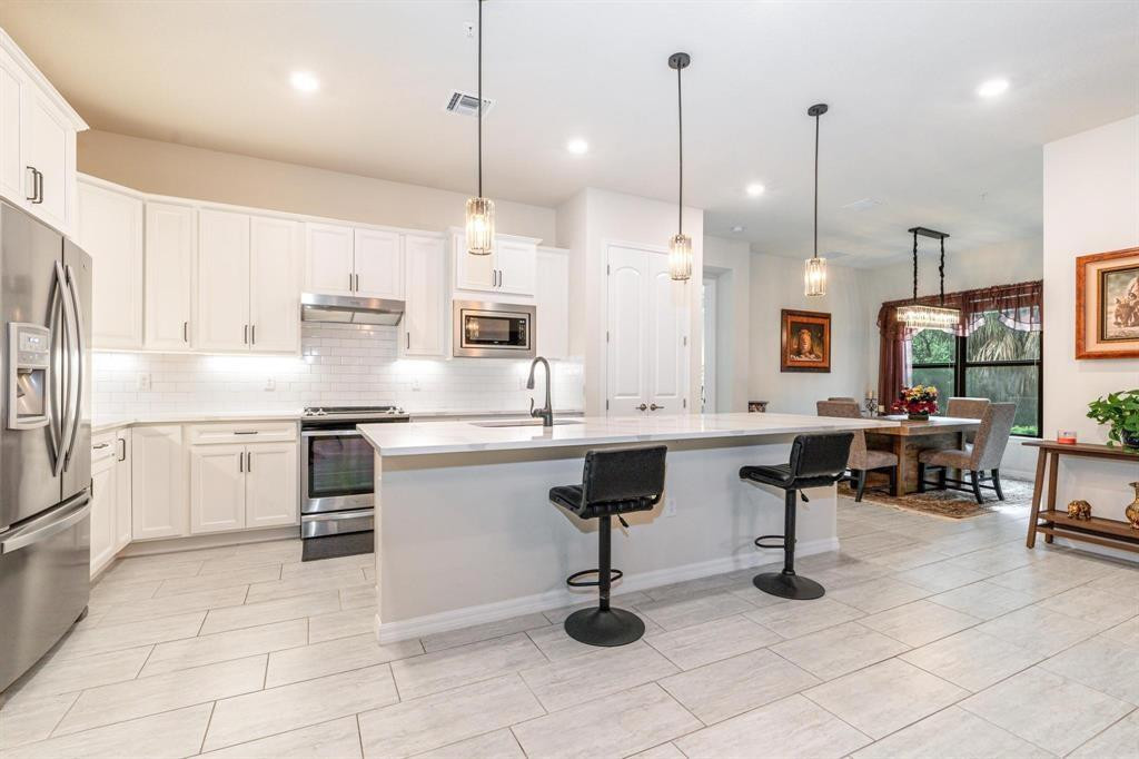 9208 Passiflora Way, Unit 102 Boca Raton, FL 33428 - Photo 12 of 30 a kitchen with stainless steel appliances kitchen island granite countertop a sink a stove a refrigerator and island with wooden floor