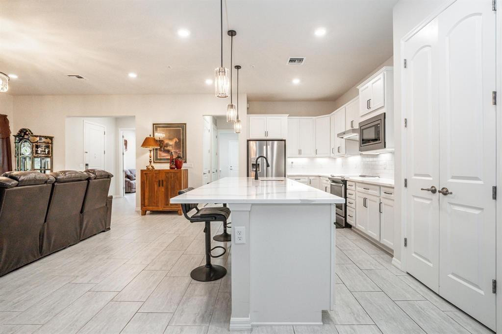 9208 Passiflora Way, Unit 102 Boca Raton, FL 33428 - Photo 15 of 30 a kitchen with stainless steel appliances kitchen island granite countertop a refrigerator and a sink