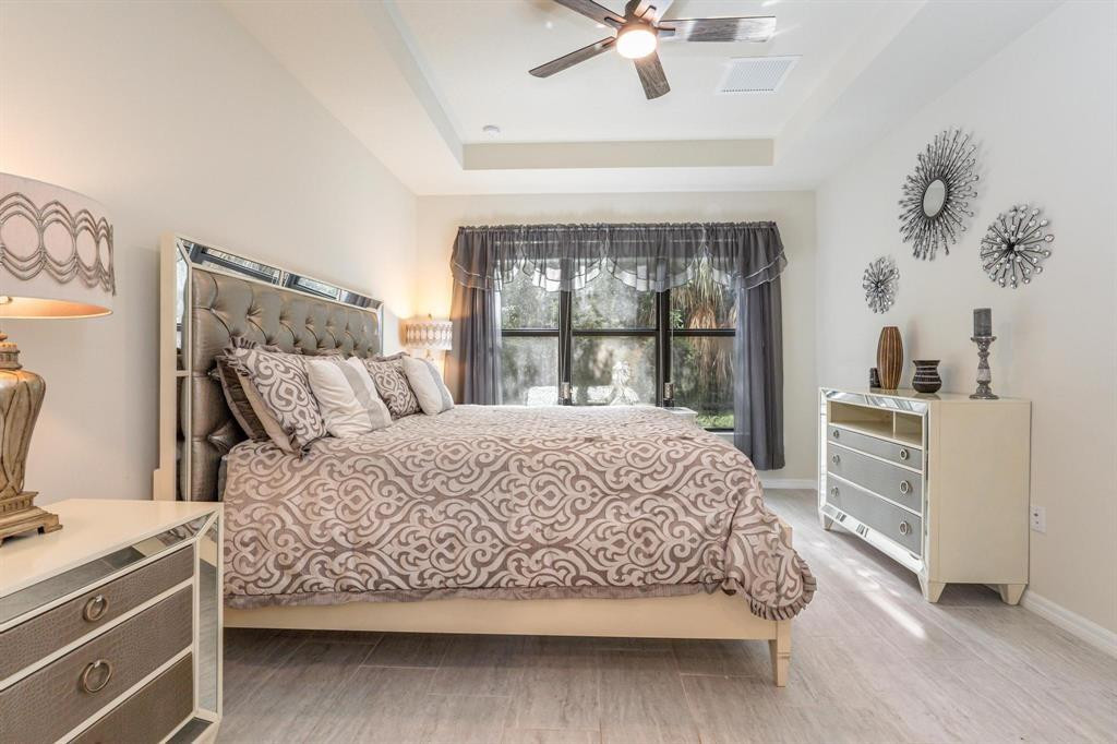 9208 Passiflora Way, Unit 102 Boca Raton, FL 33428 - Photo 23 of 30 a large bed sitting in a bedroom next to a window and a chandelier