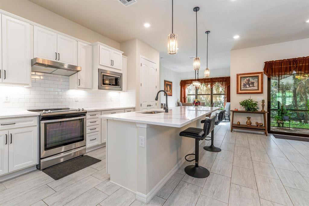 9208 Passiflora Way, Unit 102 Boca Raton, FL 33428 - Photo 27 of 30 a kitchen with stainless steel appliances kitchen island granite countertop a sink cabinets and wooden floor