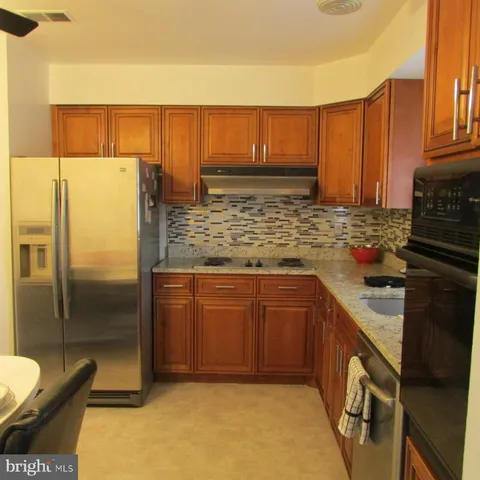 a kitchen with stainless steel appliances granite countertop a refrigerator a stove and a sink