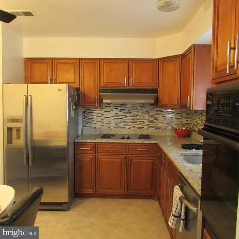 a kitchen with stainless steel appliances granite countertop a refrigerator a stove and a sink