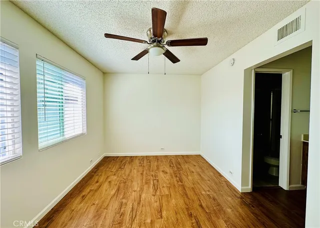 a view of empty room with wooden floor and fan