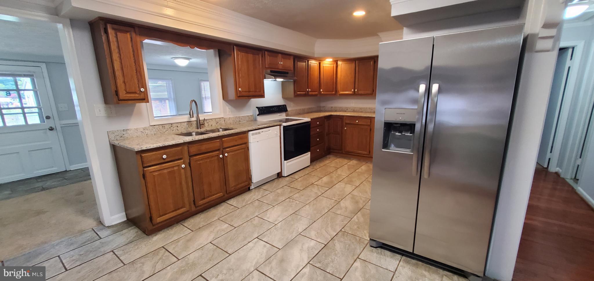 816 North Commerce Avenue, Unit B Front Royal, VA 22630 - Photo 4 of 12 a kitchen with stainless steel appliances granite countertop a refrigerator a sink a stove with wooden cabinets