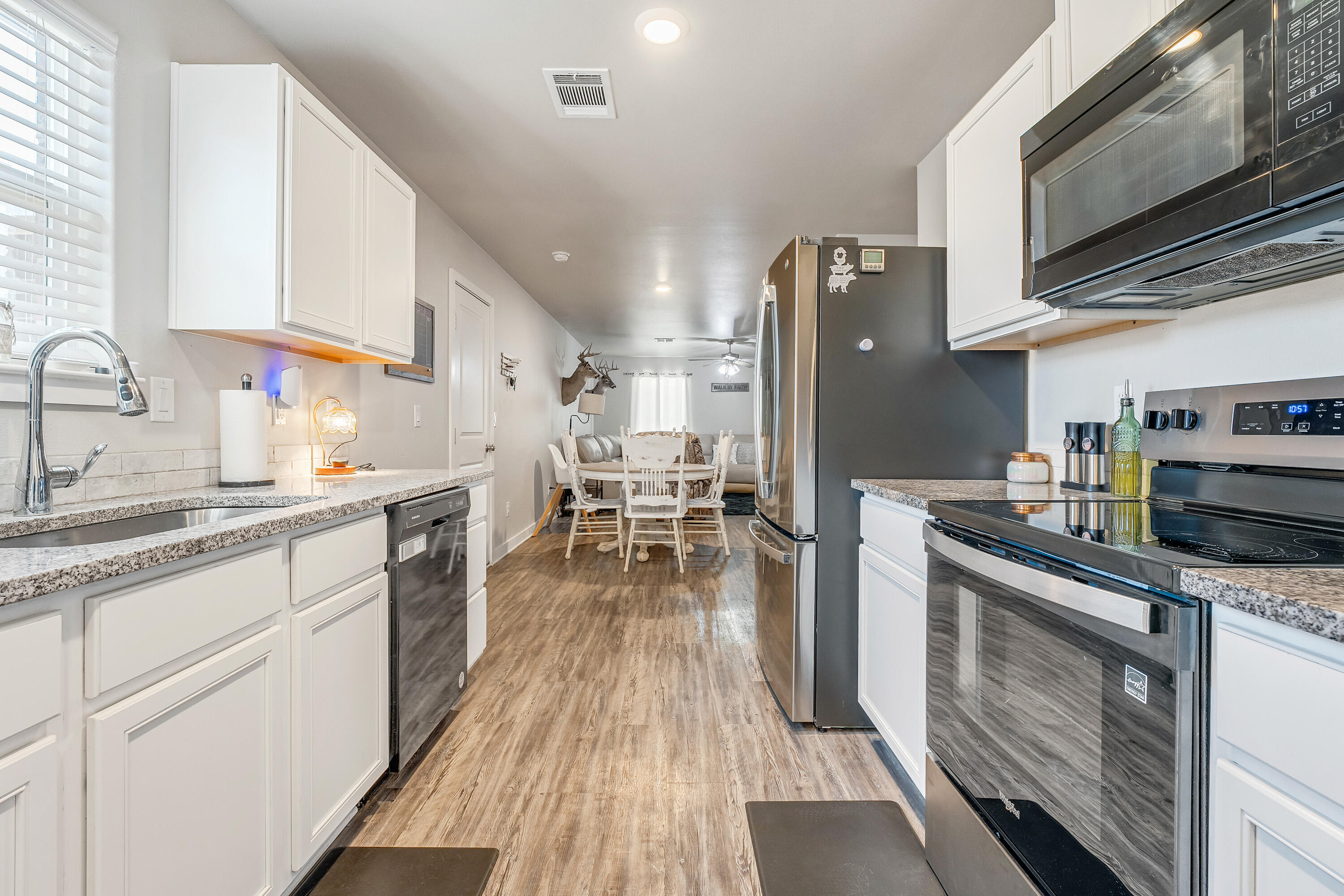 7510 28th Street Lubbock, TX 79407 - Photo 8 of 19 a kitchen with stainless steel appliances granite countertop a refrigerator a sink dishwasher a stove and white countertops with wooden floor