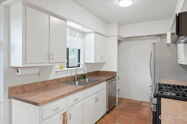 a kitchen with stainless steel appliances white cabinets and a stove top oven
