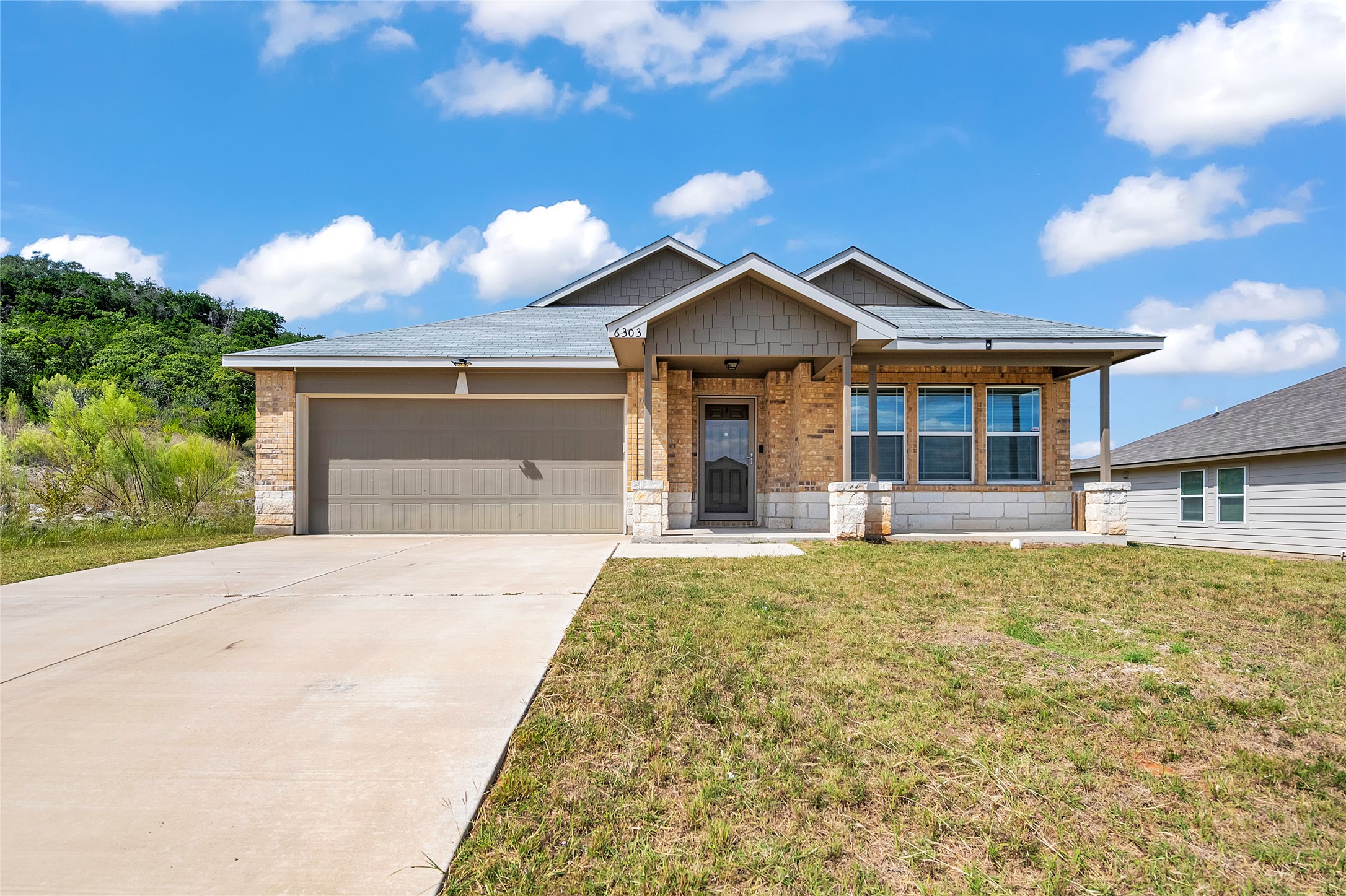 6303 Great Divide Road Killeen, TX 76549 - Photo 1 of 1 Single story home with stone siding, concrete driveway, a front lawn, a garage, and covered porch