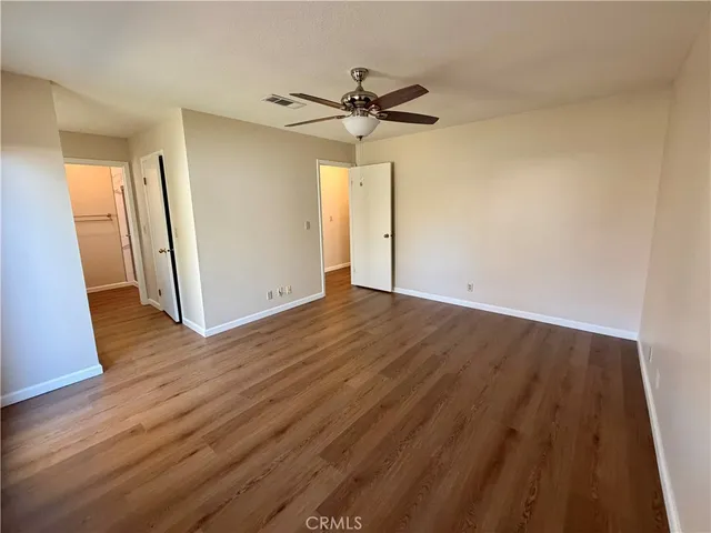 a view of a room with wooden floor and a ceiling fan
