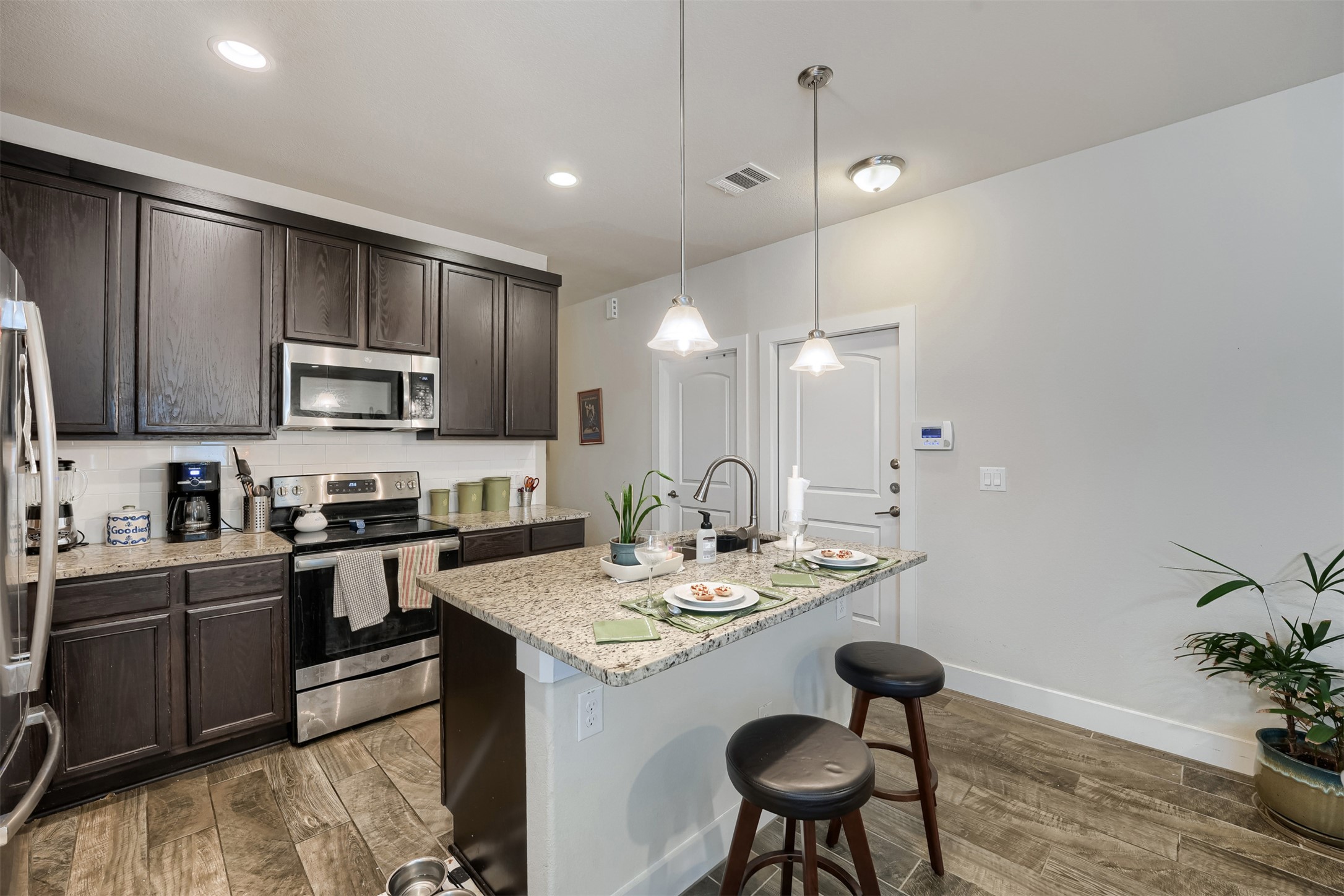 418 High Tech Drive Georgetown, TX 78626 - Photo 4 of 34 Kitchen featuring dark wood-finish cabinetry, stainless steel appliances, a white subway tile backsplash, and wood-finish flooring