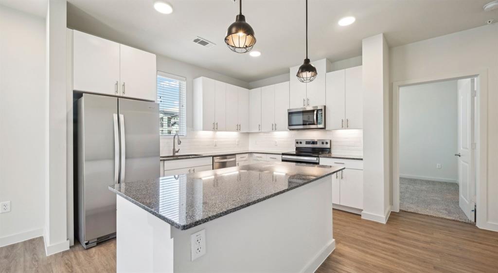 4600 East McKinney Street, Unit 5317 Denton, TX 76208 - Photo 24 of 40 a kitchen with kitchen island a counter top space cabinets and stainless steel appliances