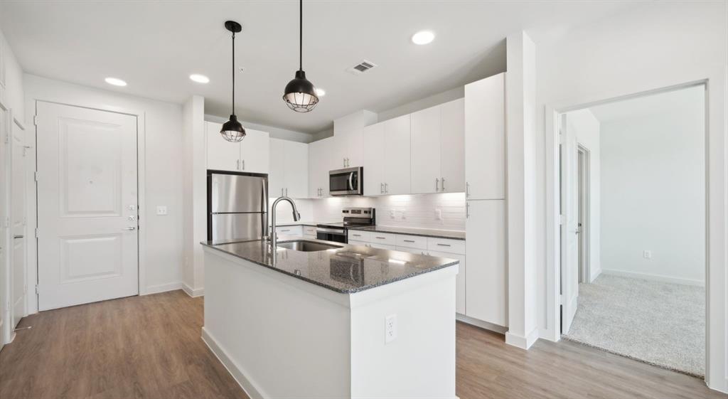 4600 East McKinney Street, Unit 5317 Denton, TX 76208 - Photo 27 of 40 a large kitchen with stainless steel appliances granite countertop a refrigerator a oven and a sink with wooden floor
