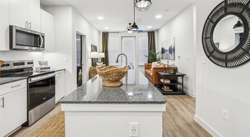 4600 East McKinney Street, Unit 5317 Denton, TX 76208 - Photo 29 of 40 a kitchen with stainless steel appliances granite countertop a sink a stove and a wooden floors