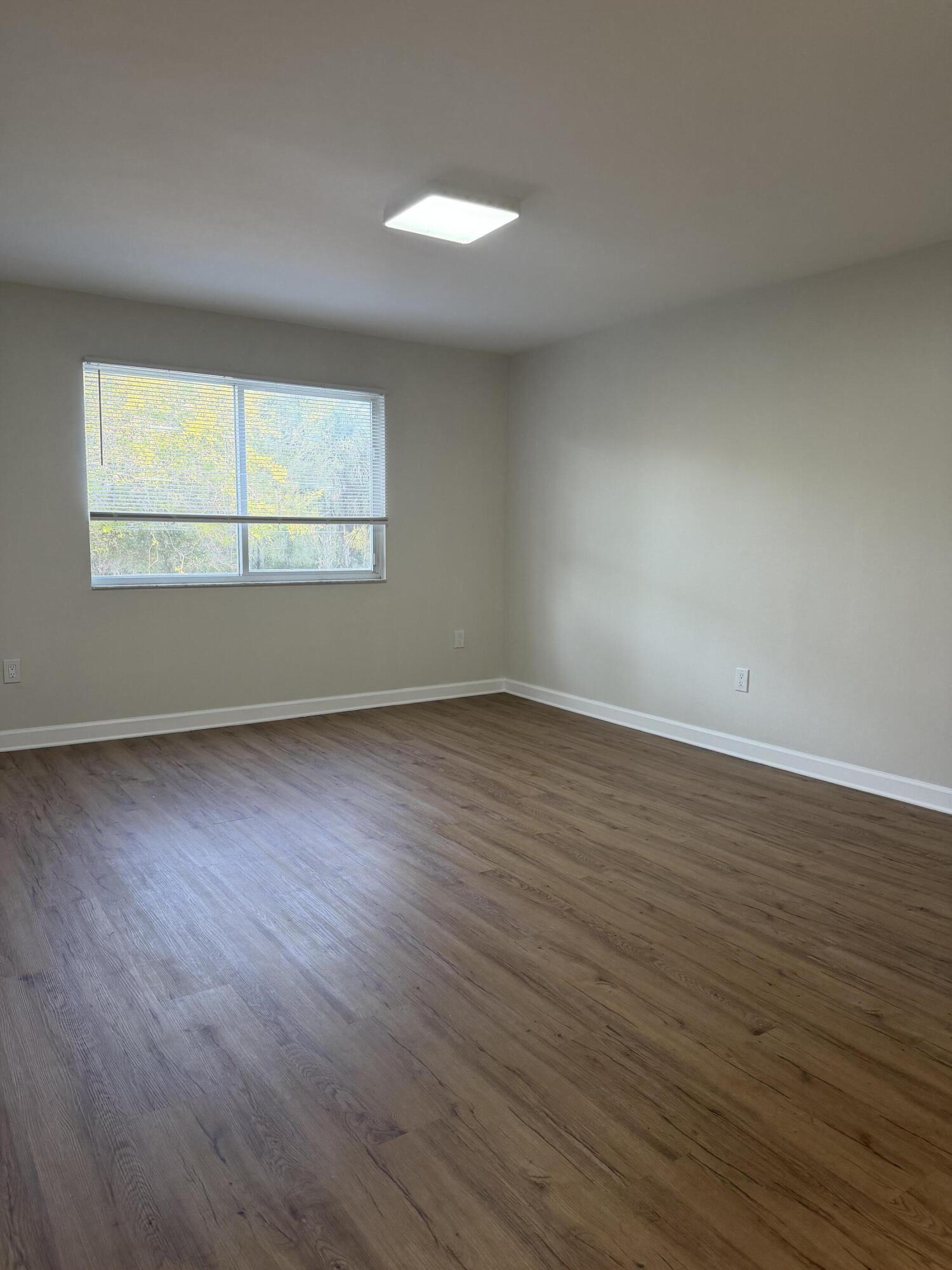 5031 Wiles Road, Unit 203 Coconut Creek, FL 33073 - Photo 14 of 24 an empty room with wooden floor and windows