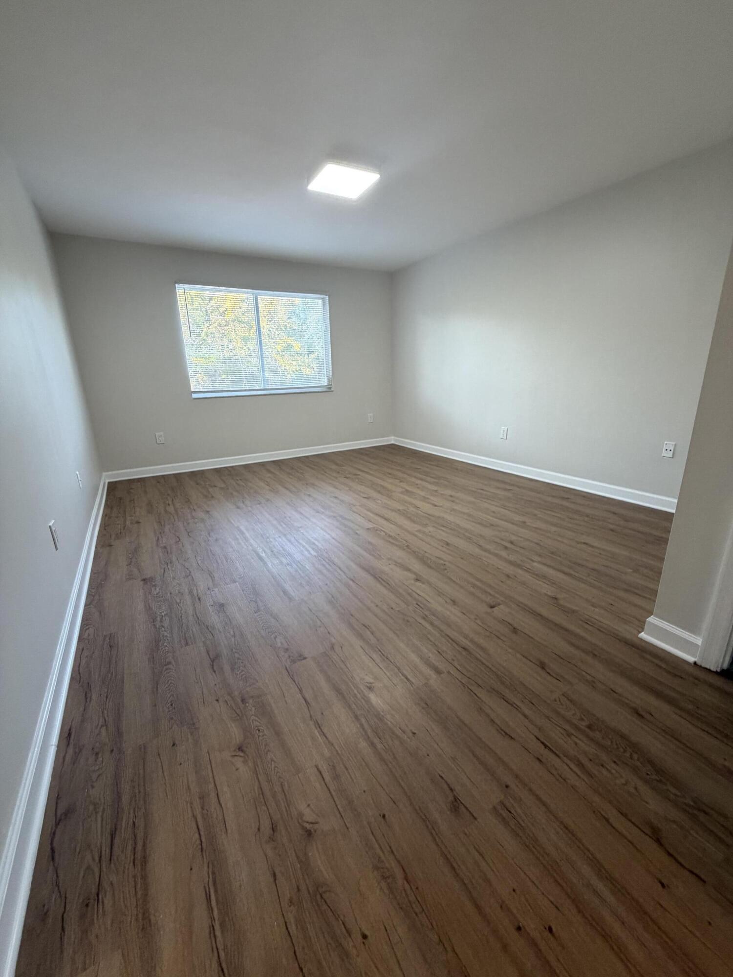 5031 Wiles Road, Unit 203 Coconut Creek, FL 33073 - Photo 15 of 24 an empty room with wooden floor and windows