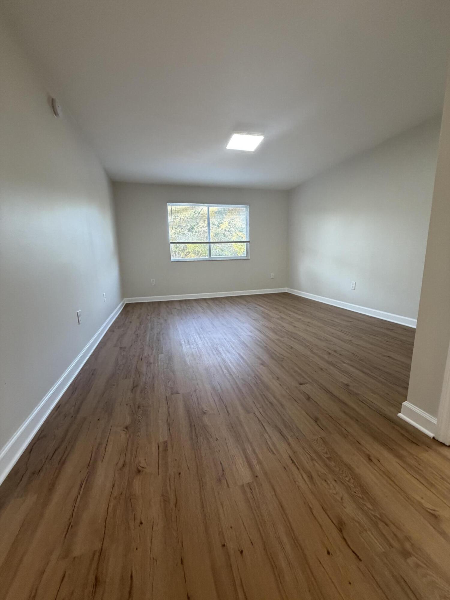 5031 Wiles Road, Unit 203 Coconut Creek, FL 33073 - Photo 17 of 24 an empty room with wooden floor and windows