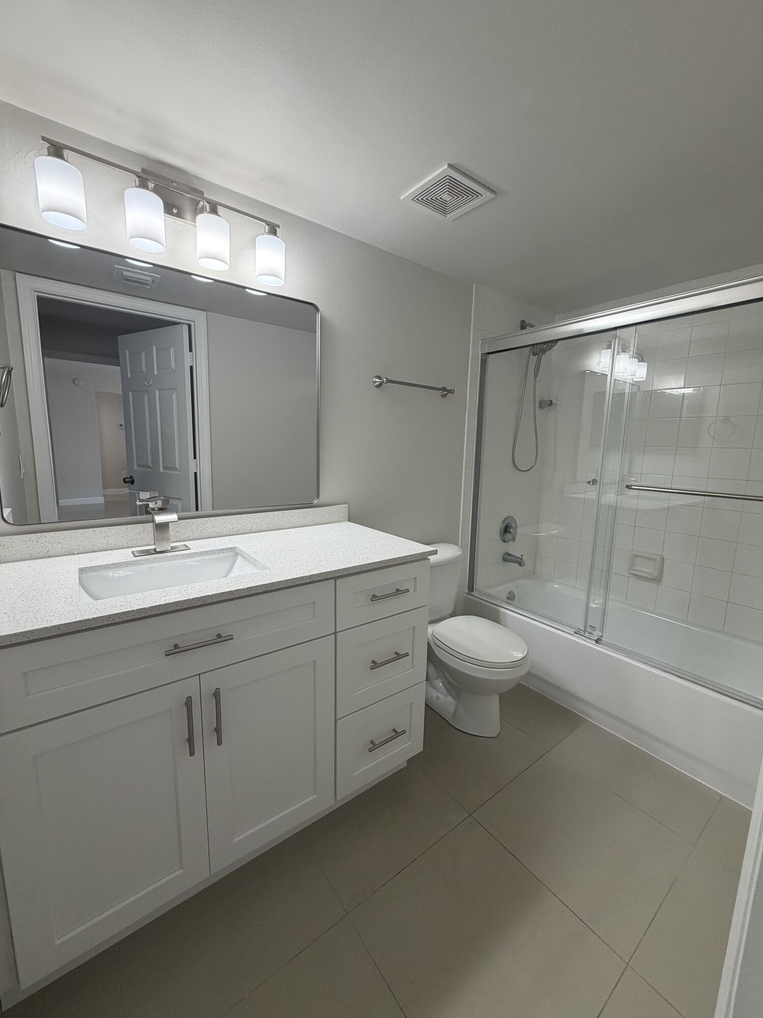 5031 Wiles Road, Unit 203 Coconut Creek, FL 33073 - Photo 18 of 24 a bathroom with a double vanity sink toilet mirror and shower