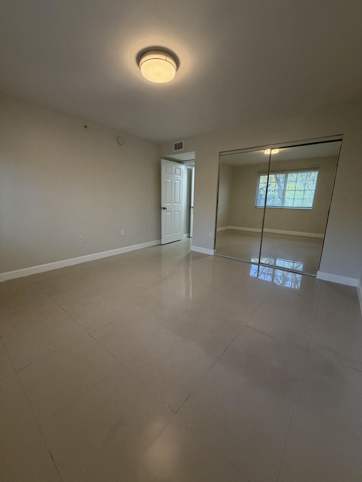5031 Wiles Road, Unit 203 Coconut Creek, FL 33073 - Photo 21 of 24 an empty room with windows and mirror