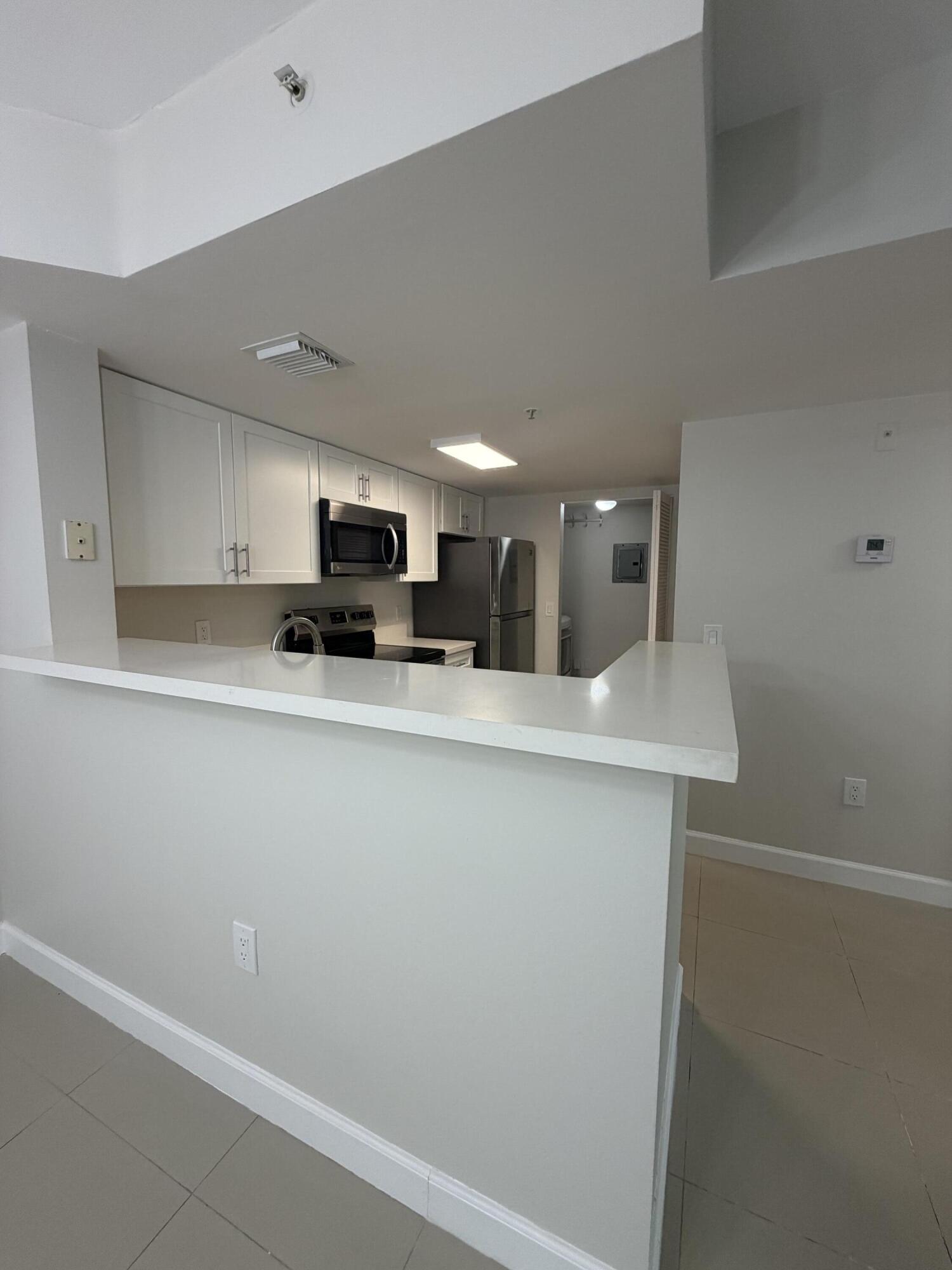 5031 Wiles Road, Unit 203 Coconut Creek, FL 33073 - Photo 8 of 24 a kitchen with stainless steel appliances a refrigerator sink and microwave