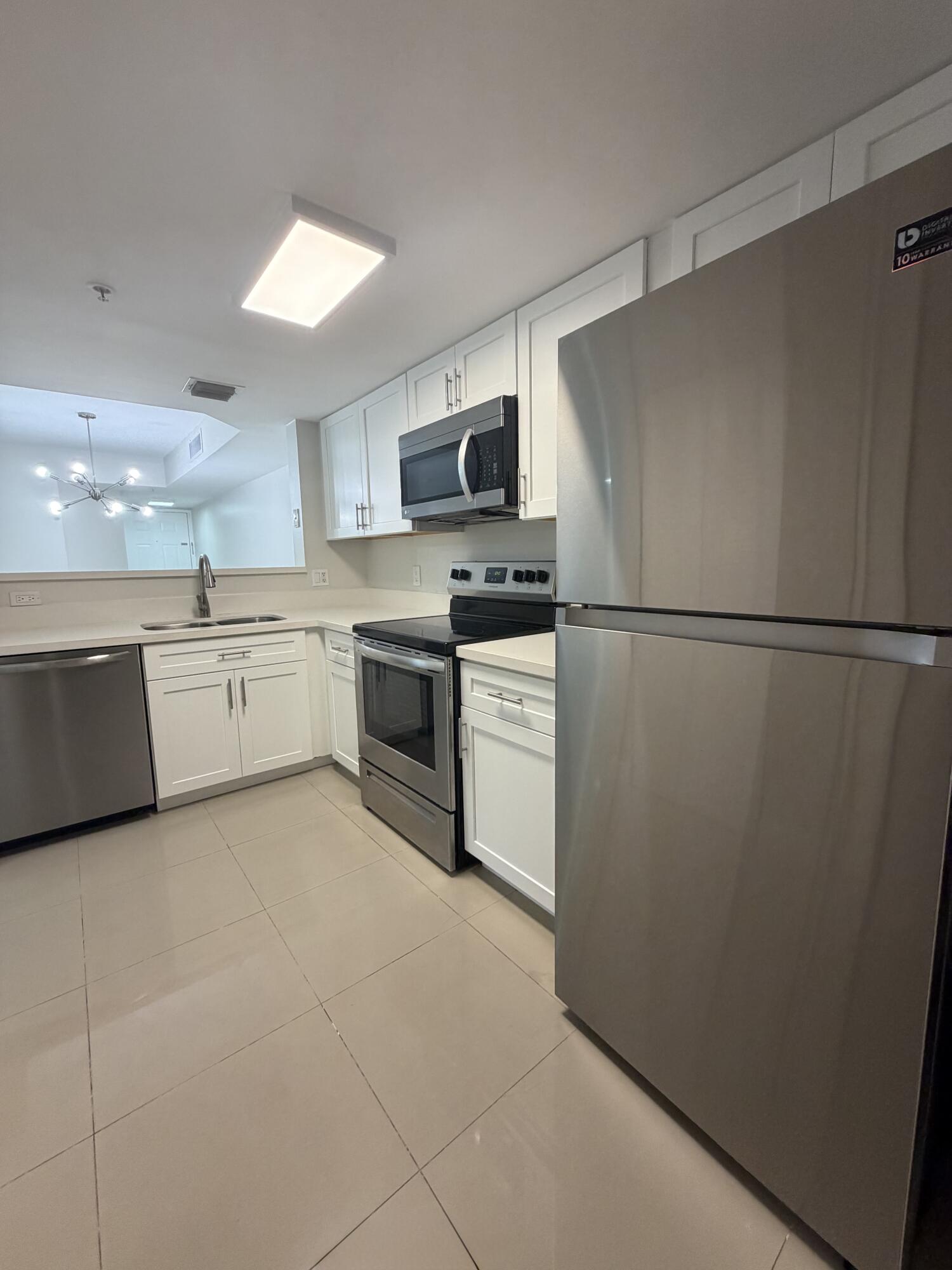5031 Wiles Road, Unit 203 Coconut Creek, FL 33073 - Photo 9 of 24 a kitchen with white cabinets and white appliances