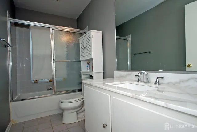 a bathroom with a shower sink vanity mirror and toilet