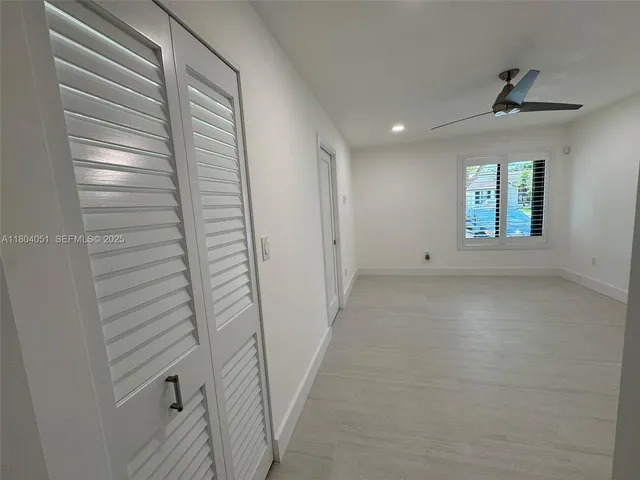 an empty room with windows and ceiling fan