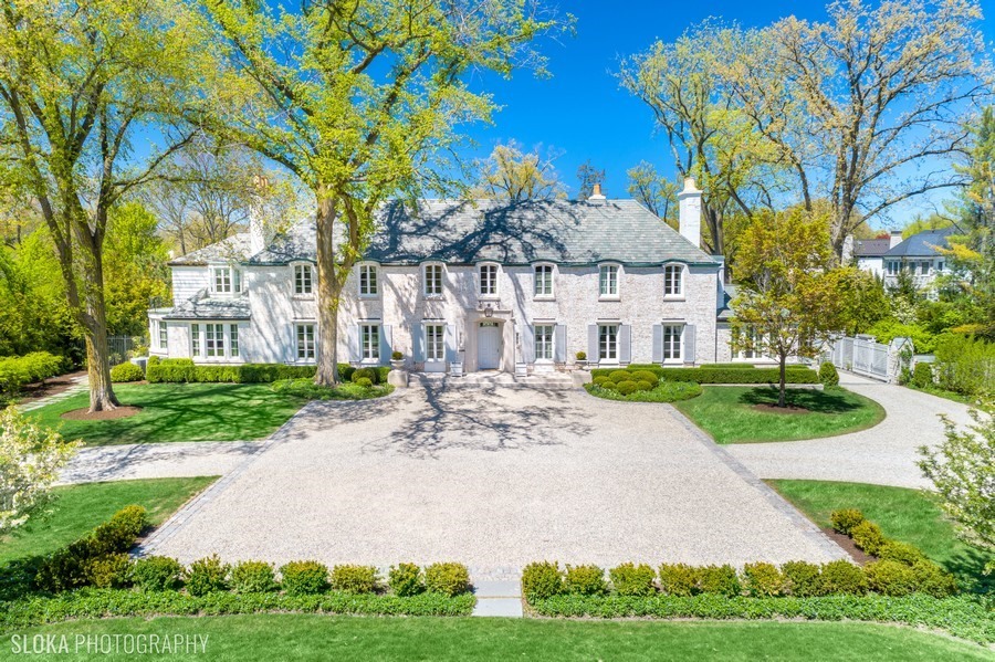 a view of a white house with a big yard plants and large trees