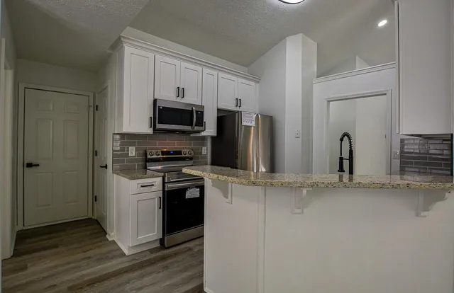 a kitchen with granite countertop a refrigerator and a stove top oven