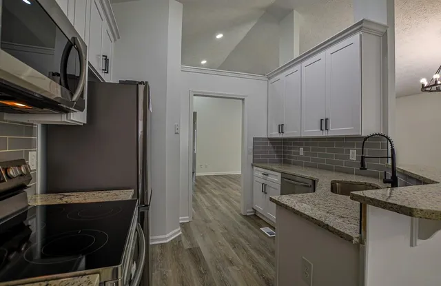 a kitchen with granite countertop white cabinets and white appliances