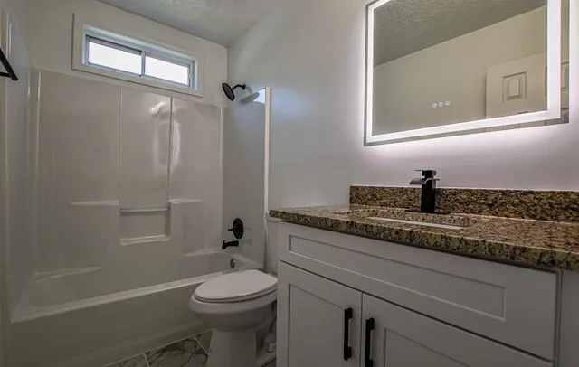 a view of an empty room with wooden floor and stairs