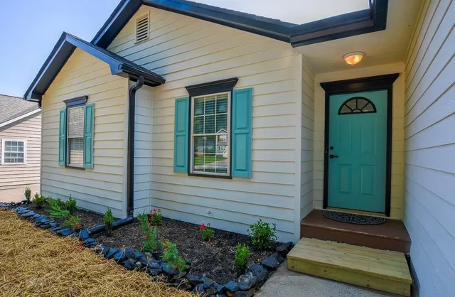 an empty room with wooden floor a ceiling fan a fireplace and windows