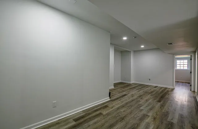 an empty room with wooden floor and windows