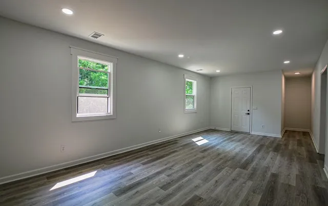 an empty room with wooden floor and windows