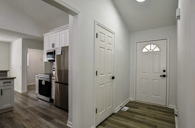 an empty room with wooden floor a ceiling fan a fireplace and windows