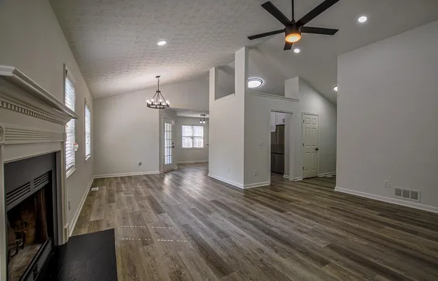 a view of an empty room with wooden floor and a ceiling fan