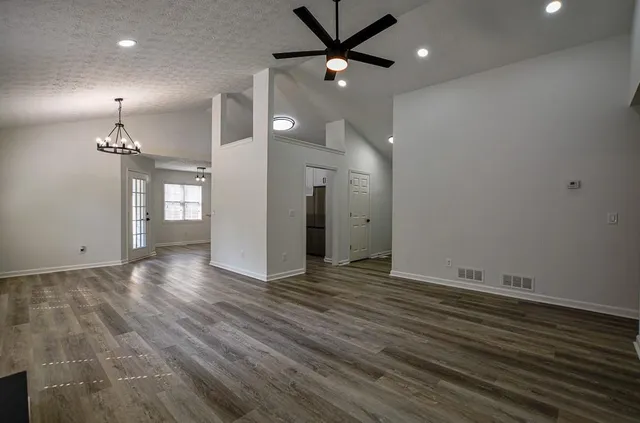 an empty room with wooden floor a fireplace and windows
