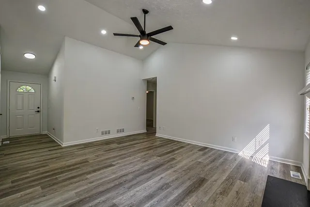 a view of an empty room with wooden floor and a window