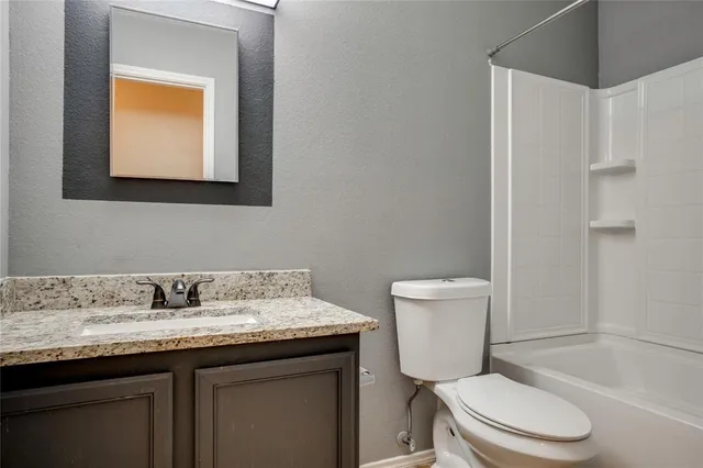 a bathroom with a granite countertop toilet sink and mirror