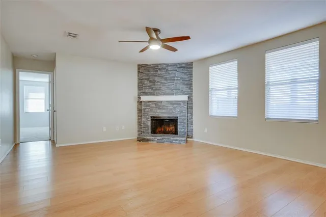 a view of an empty room with wooden floor fireplace and a window