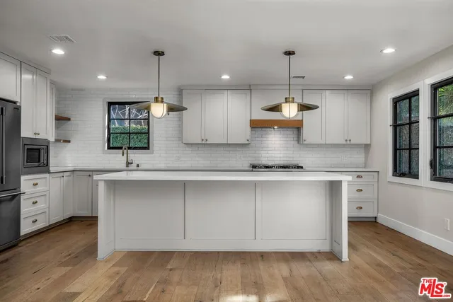 a kitchen with kitchen island granite countertop a sink a center island stainless steel appliances and cabinets