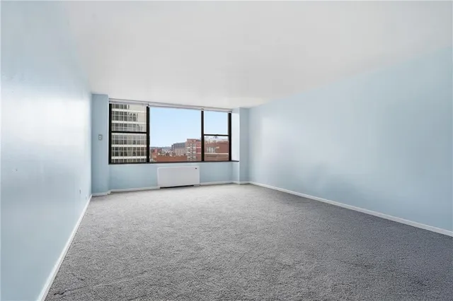 a view of an empty room with a window and fireplace