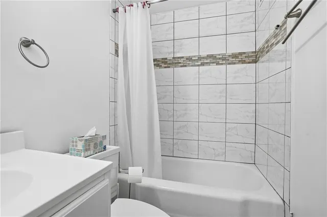 a bathroom with a granite countertop sink a toilet and shower
