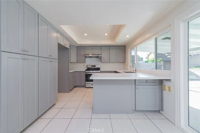 a kitchen with white cabinets appliances and window