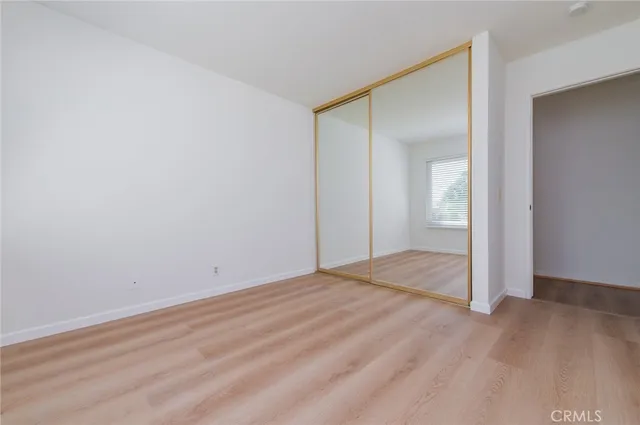 an empty room with wooden floor and mirror