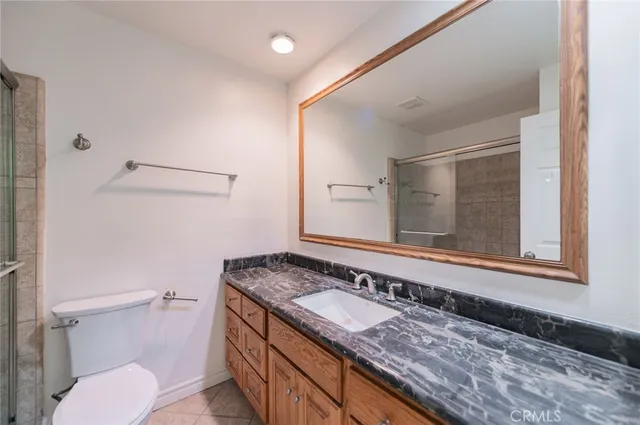 a bathroom with a granite countertop sink and a toilet