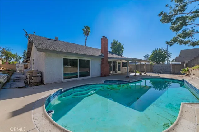 a view of a house with backyard sitting area and swimming pool