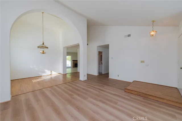 a view of an empty room with wooden floor and windows